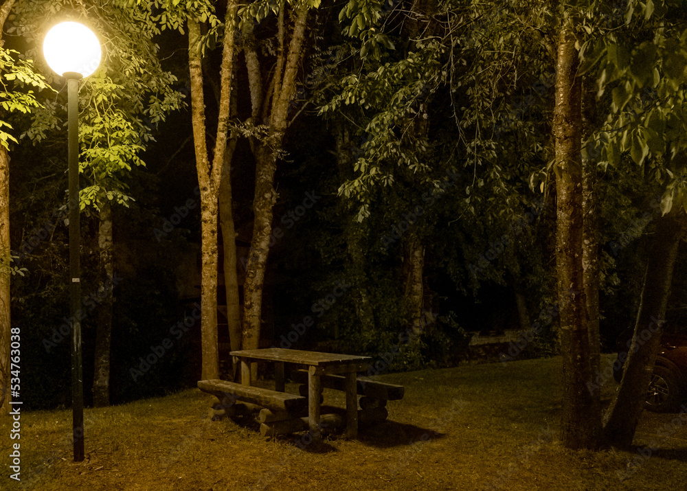 Wooden picnic table in a city park during the night Wooden picnic table in a city park during the night