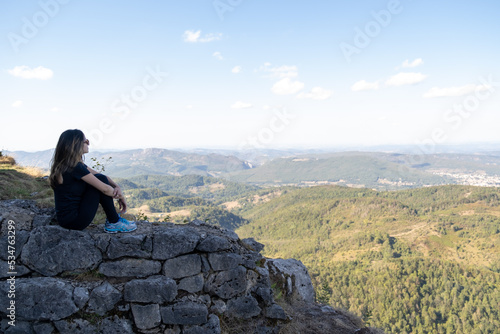Young woman seated and looking to the horizon from the ruines of the Montsegur castle in France © Otávio Pires