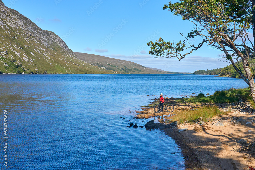 nice senior woman on mountain bike, cycling at Lough Beagh in the Glenveagh National park, near Churchill, Donegal, northern Republic of Ireland