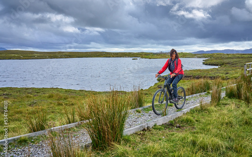nice senior woman on mountain bike, cycling in the bog Area near Derrycunlagh, County Galway, in the western part of the Republic of Ireland