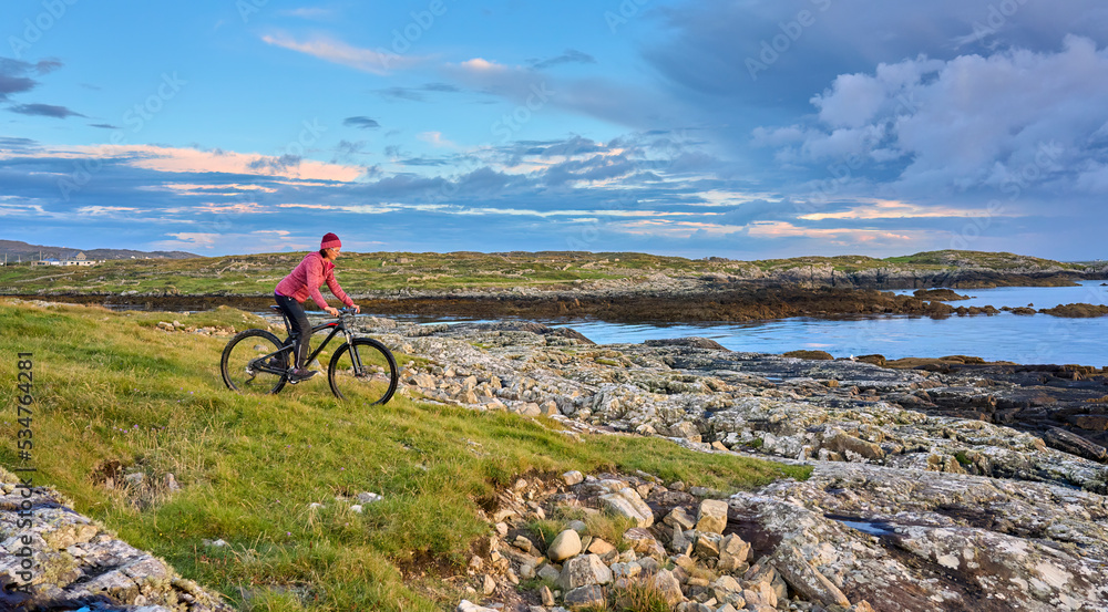 nice senior woman on mountain bike, cycling in sunset on the cliffs of Sillerna, Grallagh, County Galway, in the western part of the Republic of Ireland nice senior woman on mountain bike, cycling in sunset on the cliffs of Sillerna, Grallagh, County Galway, in the western part of the Republic of Ireland