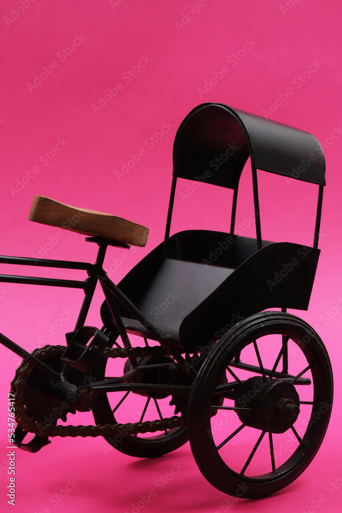 Decorative souvenir bike. Vintage three-wheeled cart on a pink background. Shallow depth of field