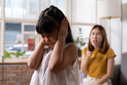 Foto Indoor shot of young Asian girl crying and cover her ear with hands and feel sad while get scold and shout with angry from her angry mother