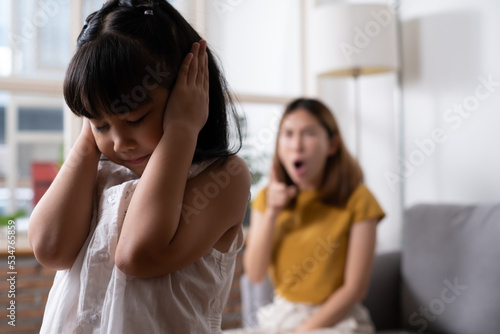 Billede på lærred Indoor shot of young Asian girl crying and cover her ear with hands and feel sad while get scold and shout with angry from her angry mother