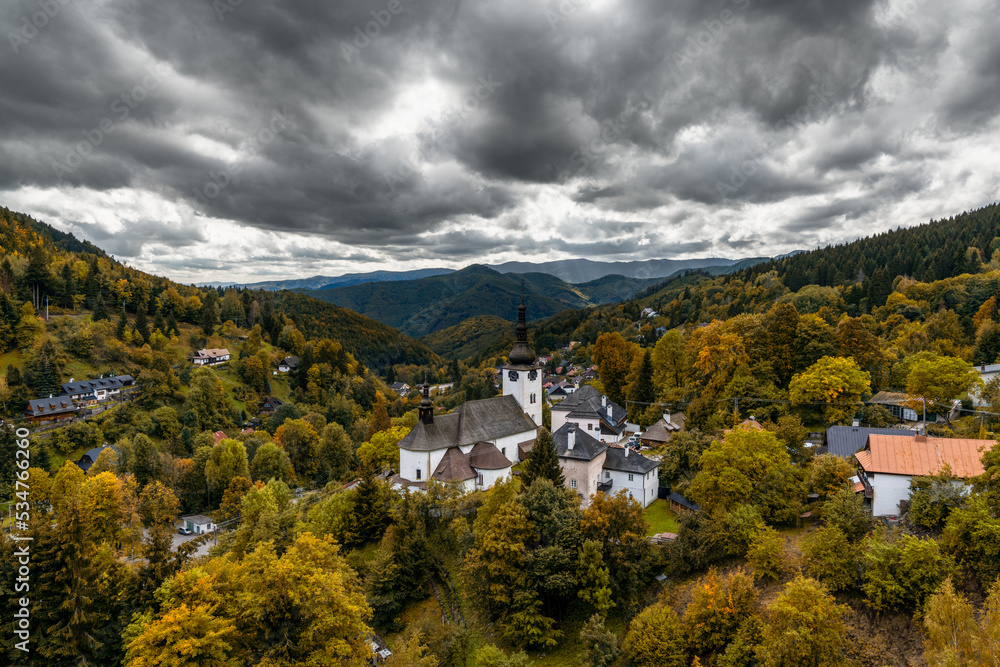 view of the village and Roman Catholic church in Spania Dolina with colorful autumn forest - obrazy, fototapety, plakaty 