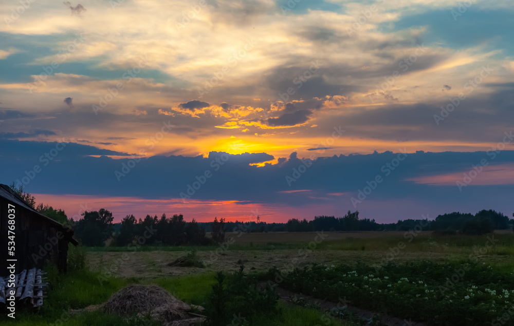 Landscape with sunset in the village in summer