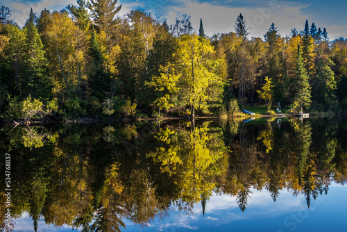 Fall colors in trees reflected on the still waters of the Madawaska River at Latchford Bridge photo