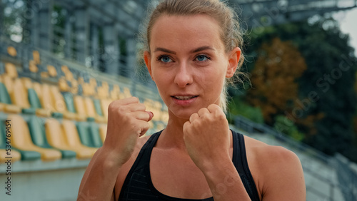 Photography Motivated female fighter athlete with clenched fists standing in boxing stance p