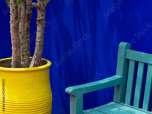 Turquoise bench on blue background next to a yellow palm pot in the Majorelle garden - Marrakech  photo