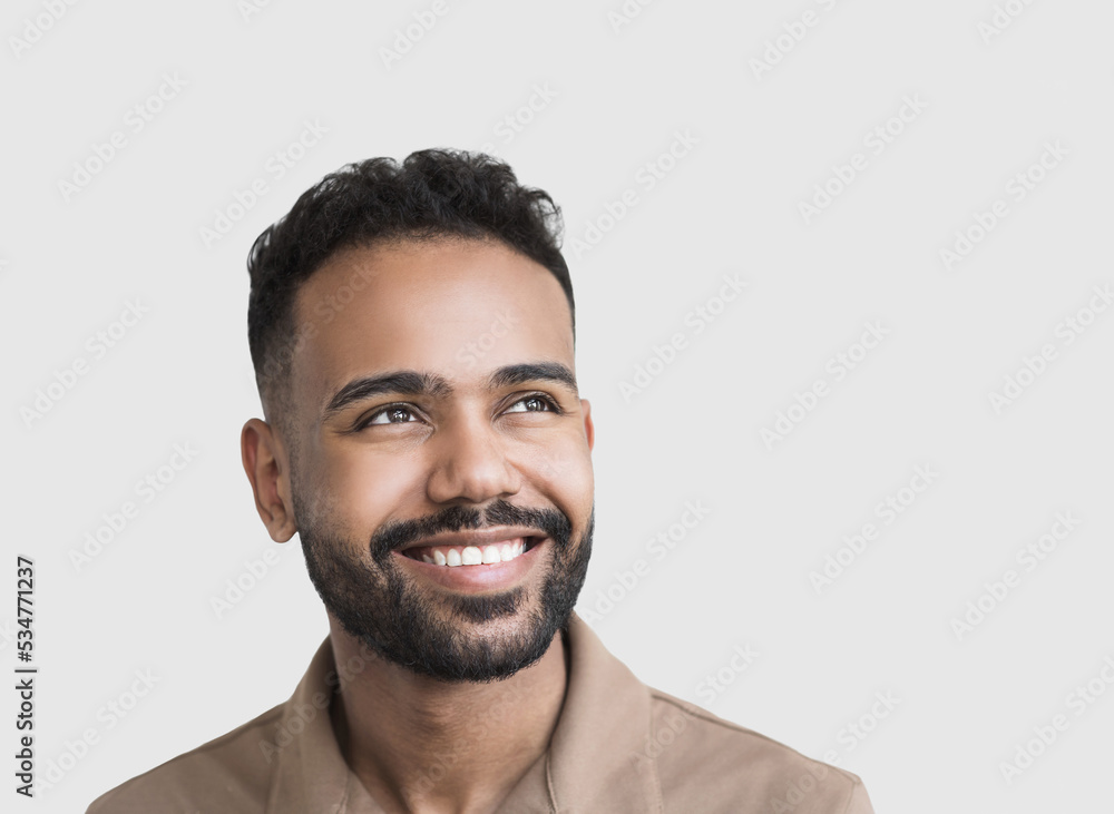 Fototapeta premium Closeup portrait of handsome smiling young man. Laughing joyful man looking up. Studio shot isolated on gray background