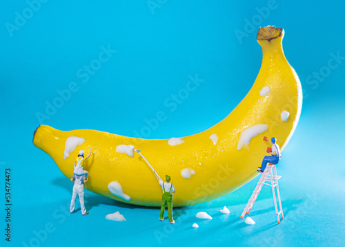 miniature people is cleaning the banana on blue background