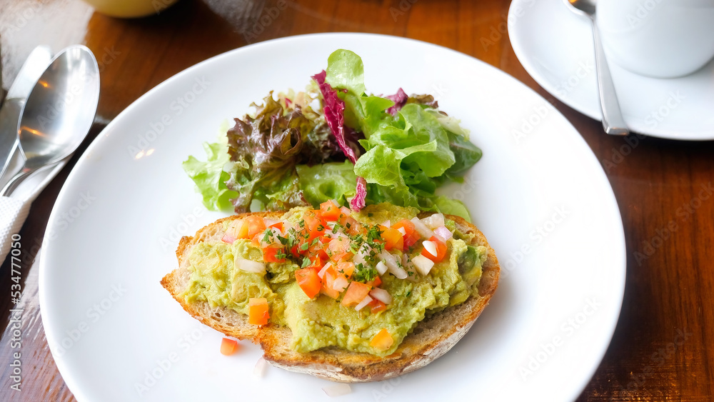 Healthy breakfast with avocado on sliced bread with tomatoes in cafe Healthy breakfast with avocado on sliced bread with tomatoes in cafe