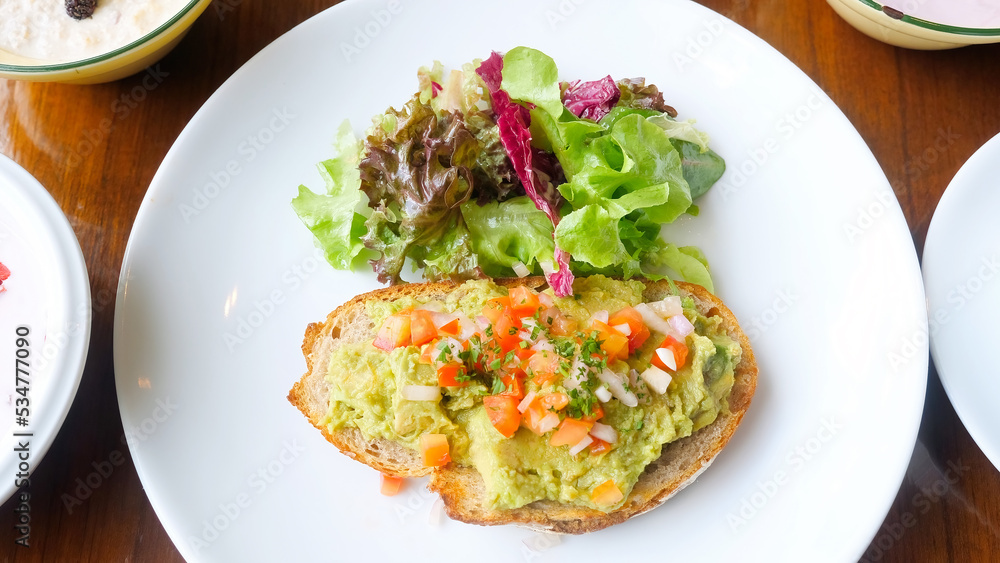Healthy vegan breakfast in cafe with avocado toast on plate Healthy vegan breakfast in cafe with avocado toast on plate