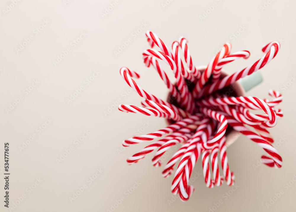 Fototapeta premium Christmas candy canes in a cup, pastel background.