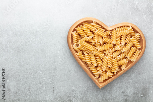 Pasta in a heart shaped wood bowl.