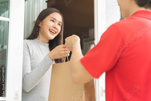 Vászonkép Postman, service shopping online asian young woman, girl hand received order, delivery man, male holding, carrying paper bag send to customer house