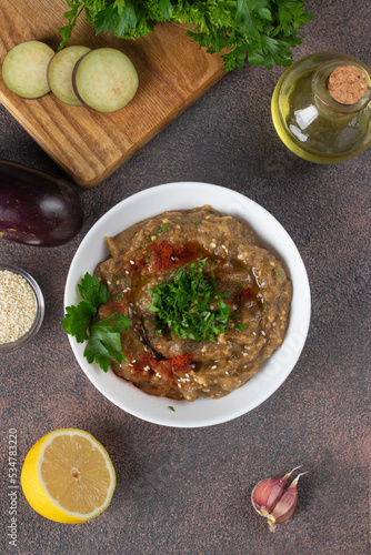 Baba ghanoush appetizer of baked eggplant with parsley, garlic, lemon and olive oil in white bowl. Arabic cuisine, Vertical image photo