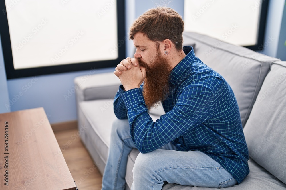 Young redhead man stressed sitting on sofa at home Young redhead man stressed sitting on sofa at home