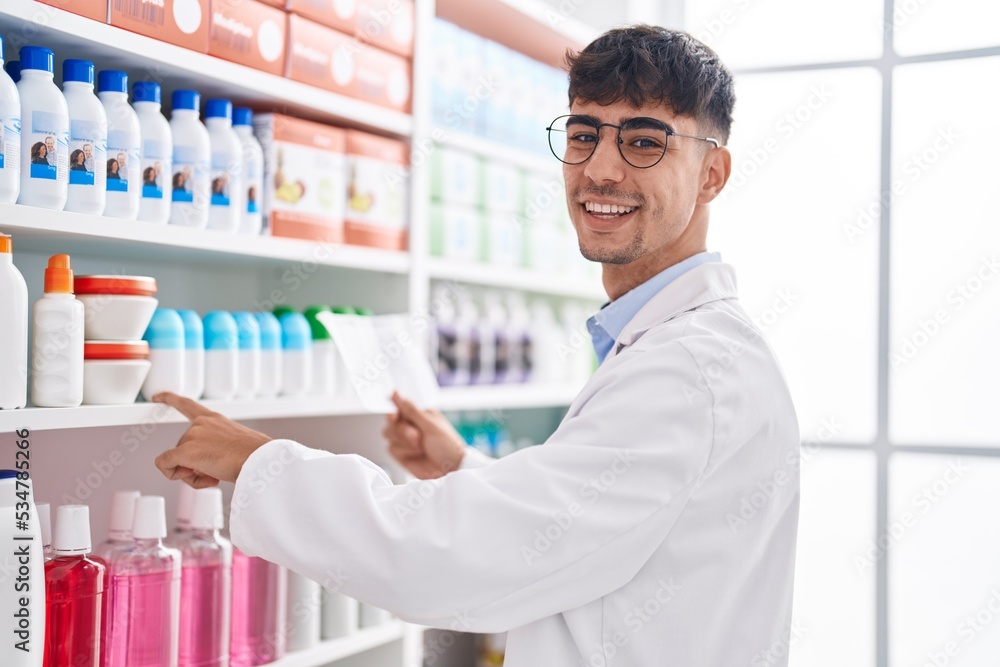 Young hispanic man pharmacist reading prescription at pharmacy