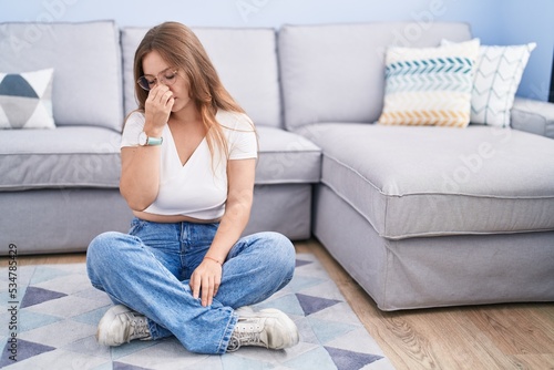 Young caucasian woman sitting on the floor at the living room tired rubbing nose and eyes feeling fatigue and headache. stress and frustration concept.