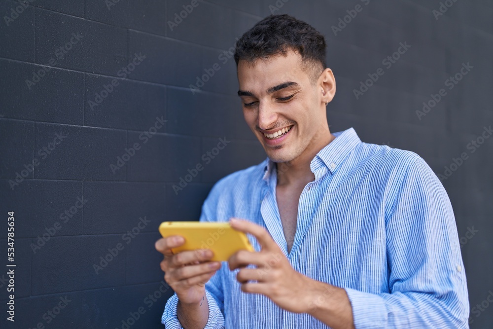 Young hispanic man smiling confident watching video on smartphone over black isolated background Young hispanic man smiling confident watching video on smartphone over black isolated background
