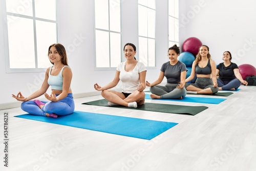 Group of young hispanic women smiling happy training yoga at sport center.