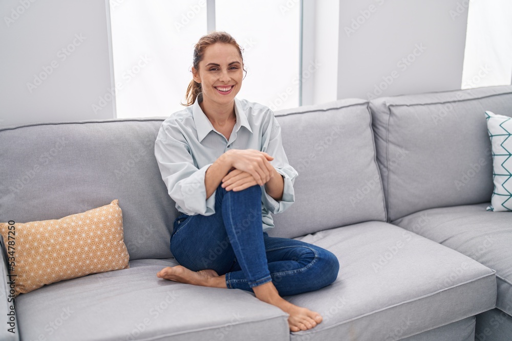 Young woman smiling confident sitting on sofa at home Young woman smiling confident sitting on sofa at home
