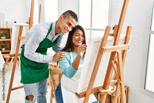 Young latin painter couple smiling happy painting at art studio