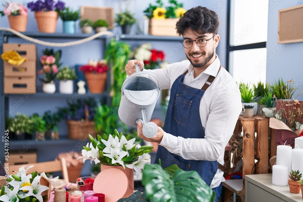 Young hispanic man florist smiling confident watering flowers at florist shop Young hispanic man florist smiling confident watering flowers at florist shop