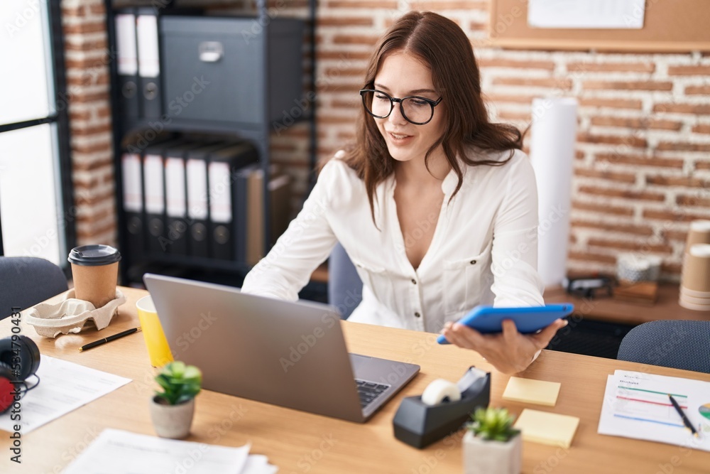 Young woman business worker using laptop and touchpad at office Young woman business worker using laptop and touchpad at office