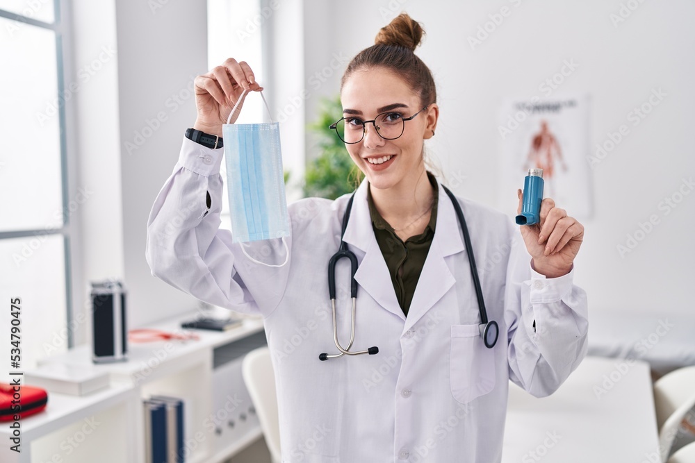 Young hispanic girl holding medical asthma inhaler at the clinic smiling with a happy and cool smile on face. showing teeth.
