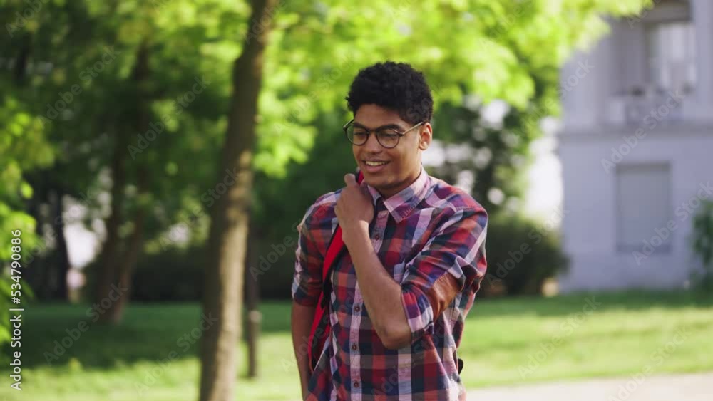 Confident smiling black student walking near college and waving hand, popularity Confident smiling black student walking near college and waving hand, popularity