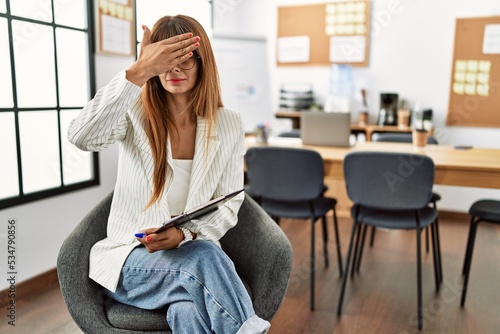 Canvastavla Hispanic business woman working at the office covering eyes with hand, looking serious and sad