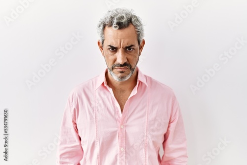 Middle age hispanic man standing over isolated background skeptic and nervous, frowning upset because of problem. negative person.