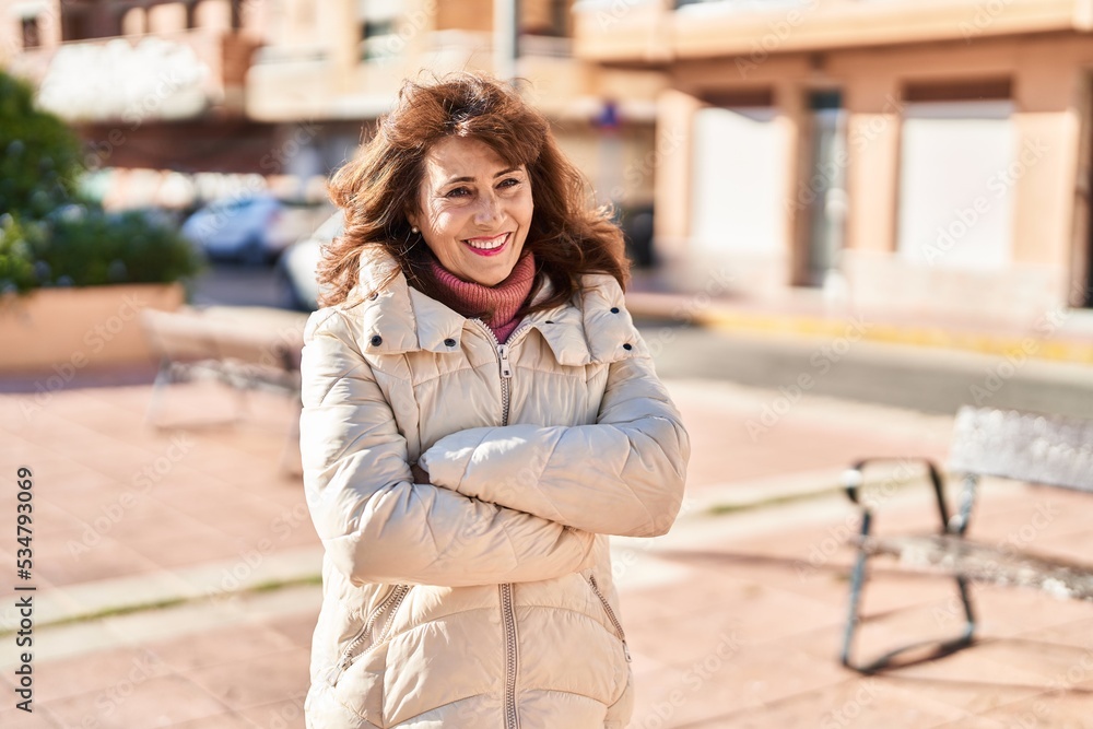Middle age woman smiling confident standing with arms crossed gesture at street