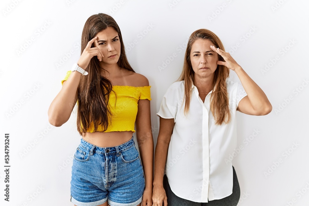Mother and daughter together standing together over isolated background pointing unhappy to pimple on forehead, ugly infection of blackhead. acne and skin problem Mother and daughter together standing together over isolated background pointing unhappy to pimple on forehead, ugly infection of blackhead. acne and skin problem