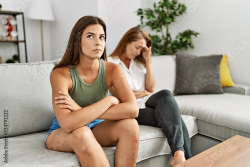 Mother and daughter unhappy arguing sitting on sofa at home