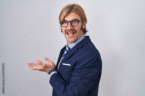 Caucasian man with mustache wearing business clothes pointing aside with hands open palms showing copy space, presenting advertisement smiling excited happy