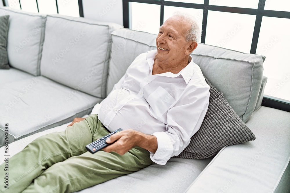 Senior man watching movie sitting on sofa at home