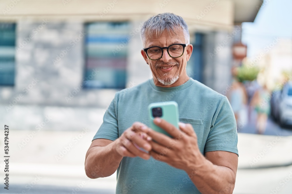 Middle age grey-haired man smiling confident using smartphone at street Middle age grey-haired man smiling confident using smartphone at street