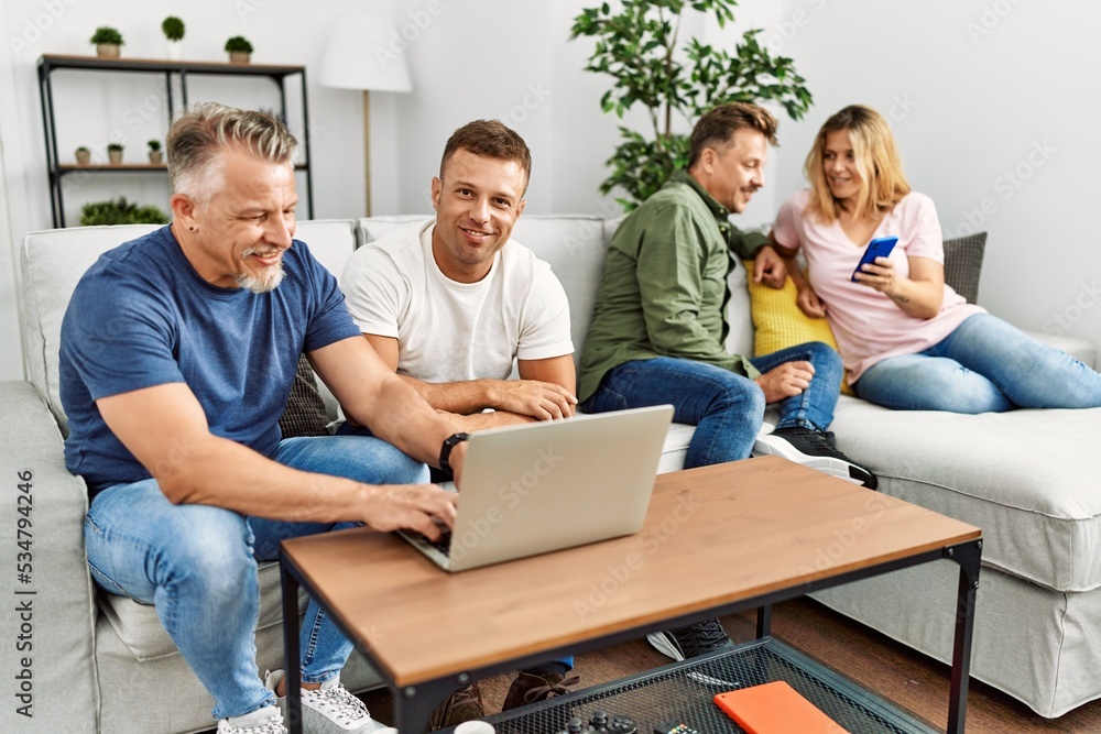 Group of middle age friends smiling happy using smartphone and laptop sitting on the sofa at home. Group of middle age friends smiling happy using smartphone and laptop sitting on the sofa at home.