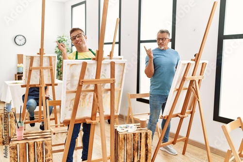 Group of middle age people artist at art studio smiling happy pointing with hand and finger to the side