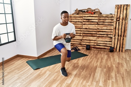 Young african man training with dumbbells at the gym