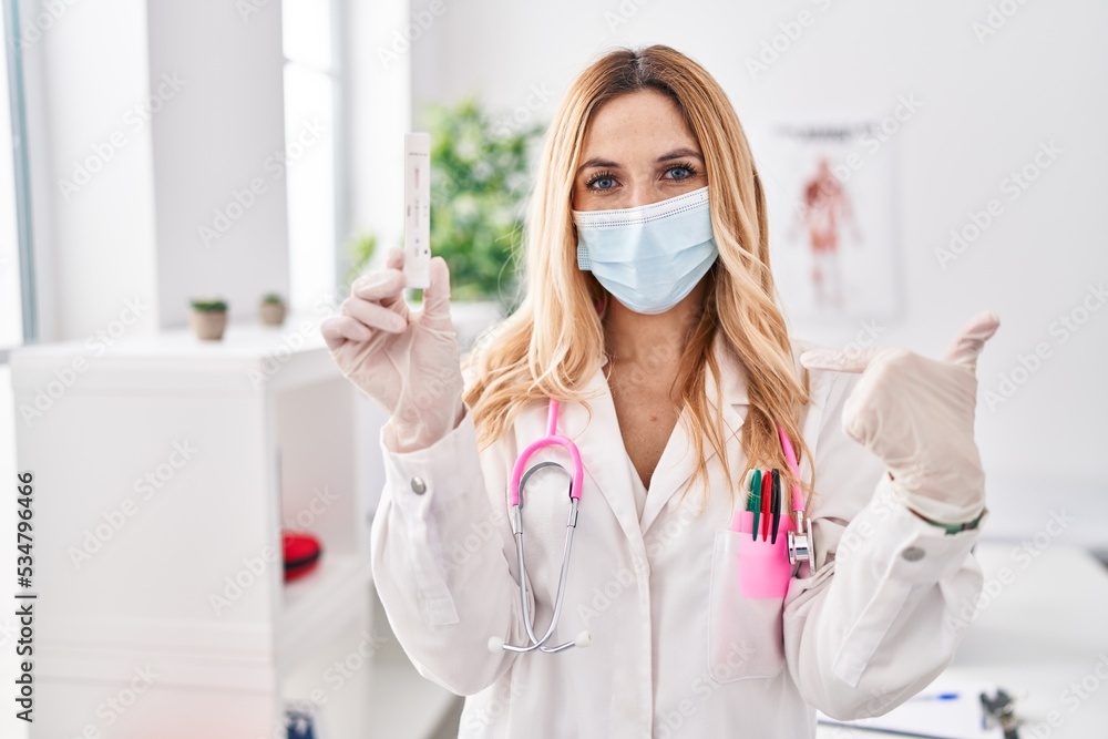 Naklejka premium Young caucasian doctor woman holding covid test pointing finger to one self smiling happy and proud