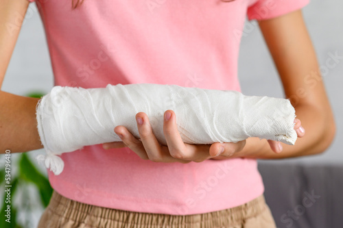 Close-up of a hand with a fracture in a cast. The concept of an accident insured event. Selective focus on bandage with plaster.