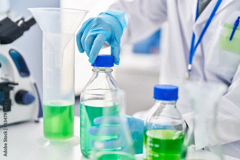 Young hispanic man wearing scientist uniform closing bottle at laboratory Young hispanic man wearing scientist uniform closing bottle at laboratory