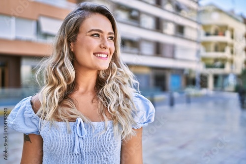 Young blonde girl smiling happy standing at the cityl photo