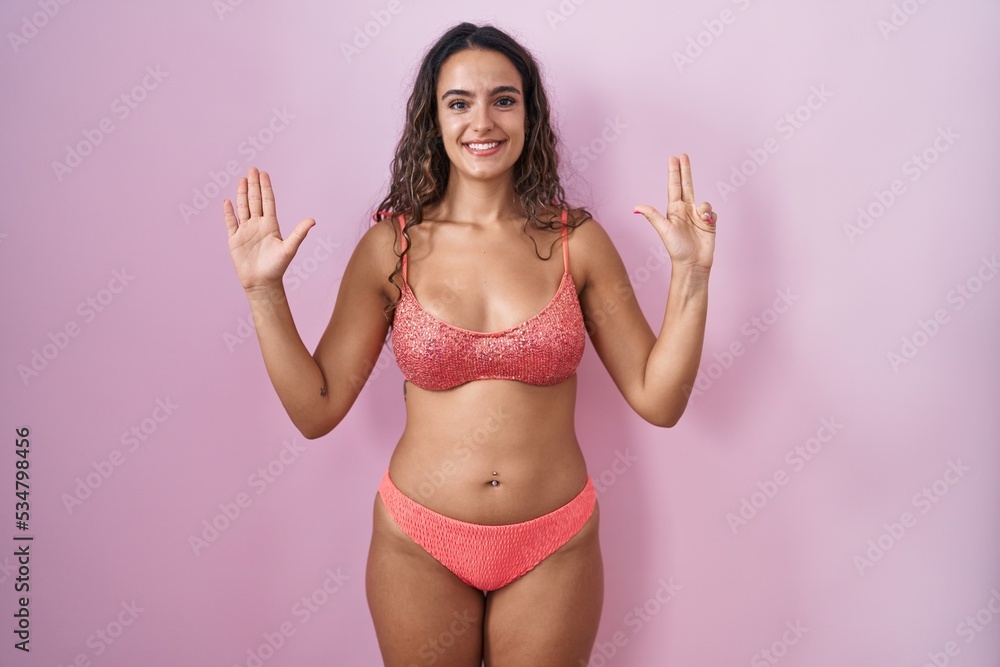 Young hispanic woman wearing lingerie over pink background showing and pointing up with fingers number eight while smiling confident and happy. Young hispanic woman wearing lingerie over pink background showing and pointing up with fingers number eight while smiling confident and happy.