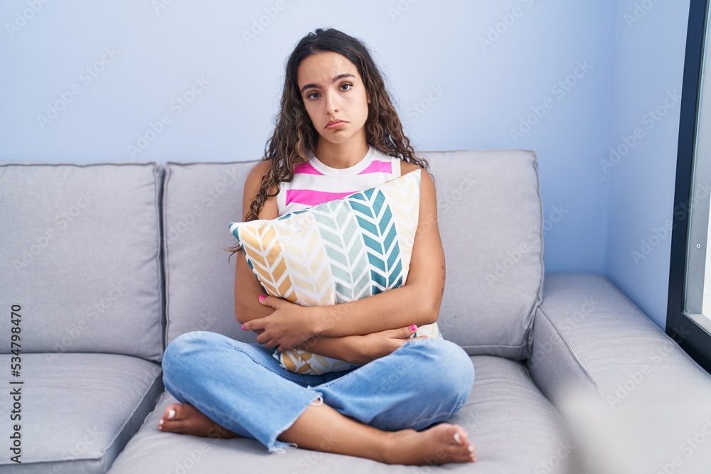 Young hispanic woman sitting on the sofa at home depressed and worry for distress, crying angry and afraid. sad expression.