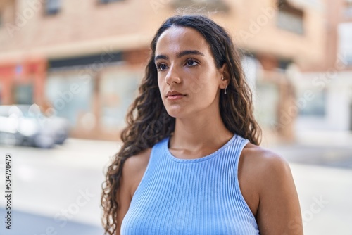 Young beautiful hispanic woman standing with serious expression at street